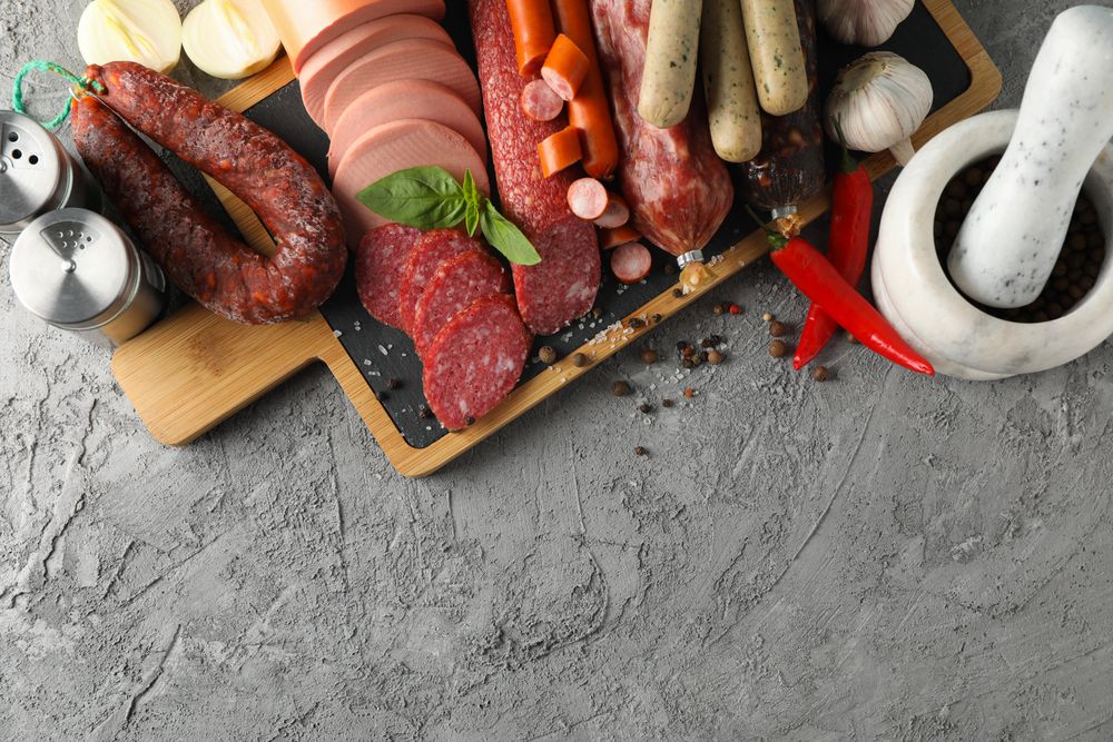 Top view of kitchen board with cured meats and mortar