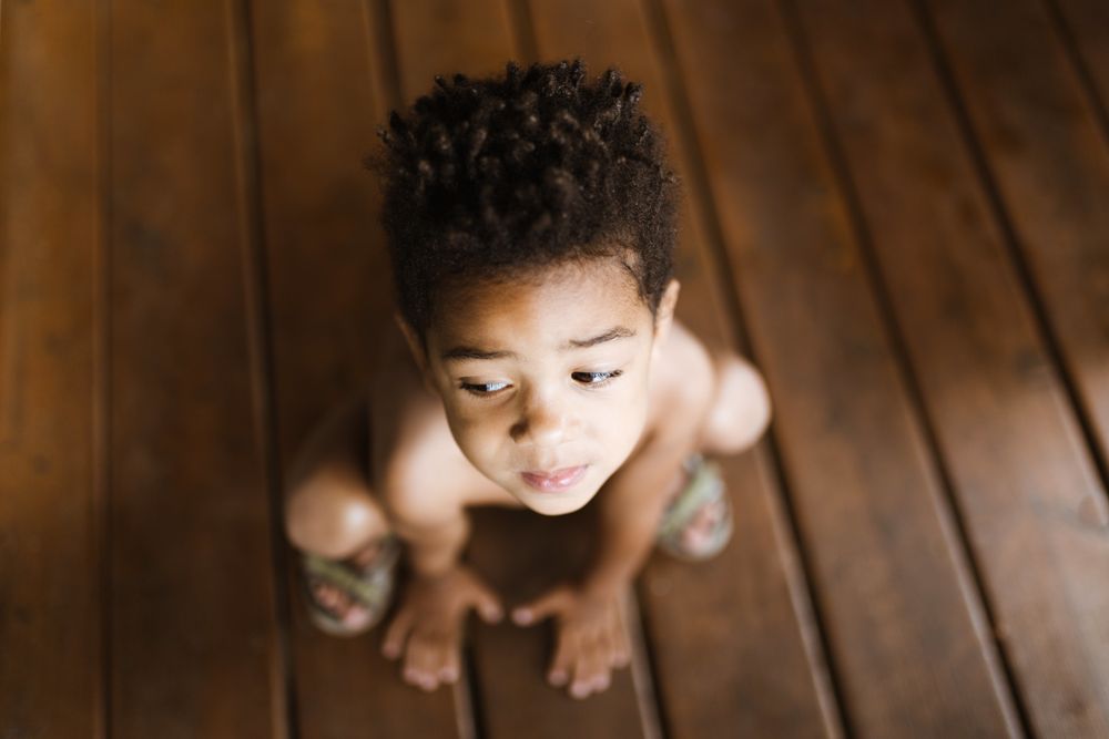 Black boy sitting on wooden floor