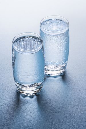 Glassess of water and tonic water on blue background