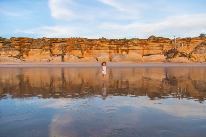 Little girl walking on water of beach seashore