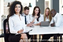 Curly haired businesswoman smiling in office looking at camera 4Aao64