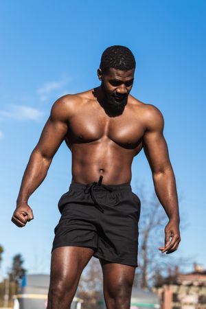 Strong Black sportsman resting during training on sports ground