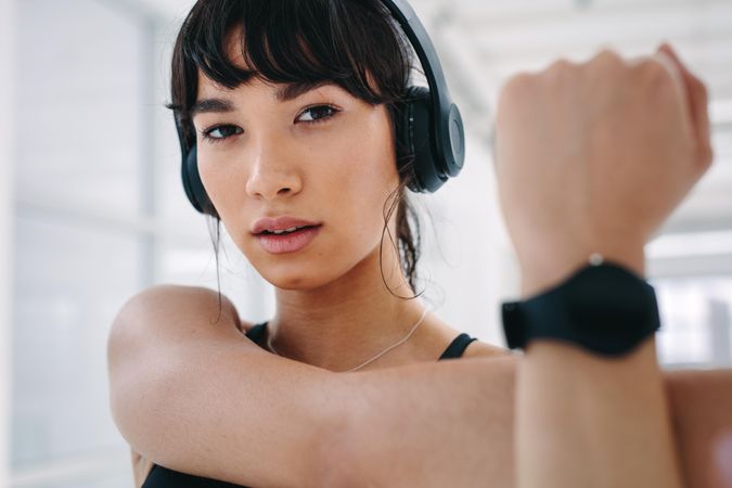 Close up of healthy woman with headphones doing arm stretching exercise
