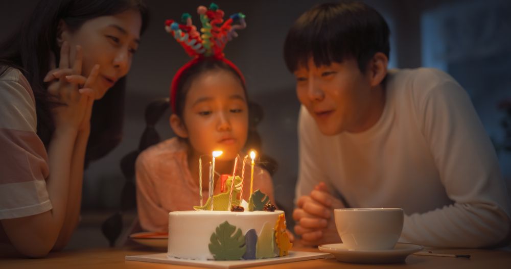 Family Memories: Portrait of Cute Little Girl Making a Wish Before Blowing Out her Birthday Cake Candles.