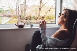Woman relaxing with tea pot and spliff by the window be9nqb