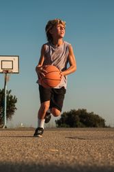 Active boy playing with basketball on court