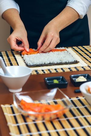 Chef hands placing salmon on rice to make sushi