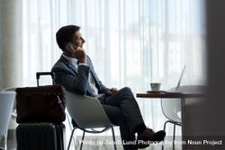 Businessman at airport lounge talking on phone 4ZeOnW