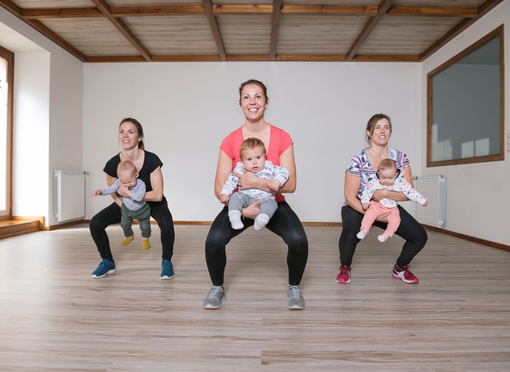 Mothers lifting babies in gym