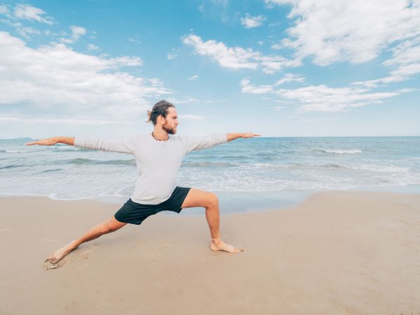 Man training yoga on beach