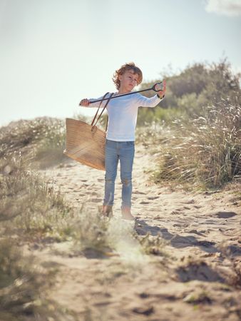Adorable preteen boy picking up garbage with trash grabber