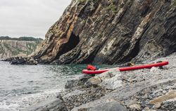 Paddle board on rocky shore near water