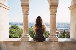 Woman sitting on columned marble fence and looking at city