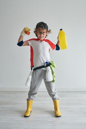 Cheerful boy holding soap and yellow bottle in hands in studio