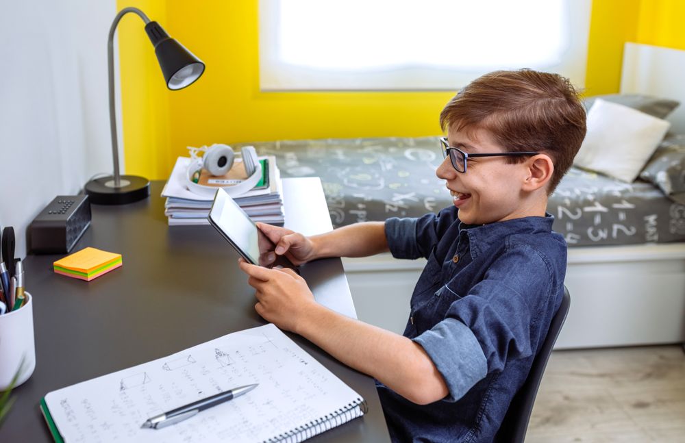 Happy preteen doing homework with a tablet