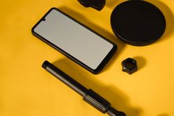 Phone with mockup screen and accessories on yellow table with shadow