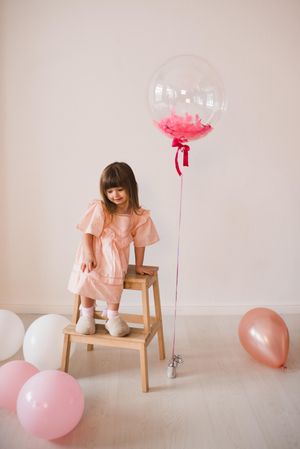 Girl in pink dress surrounded by balloons