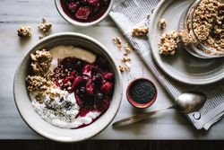Delicious breakfast bowl with quinoa, rice and groats near tea cup and newspaper