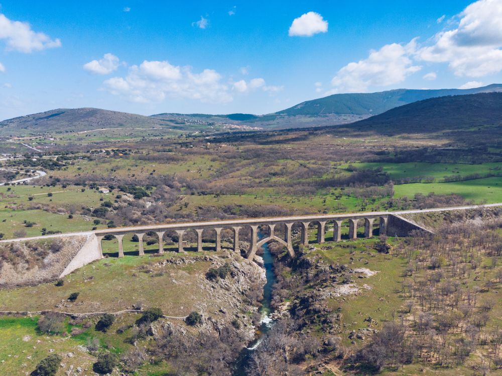 Concrete bridge over mountain river at picturesque green valley