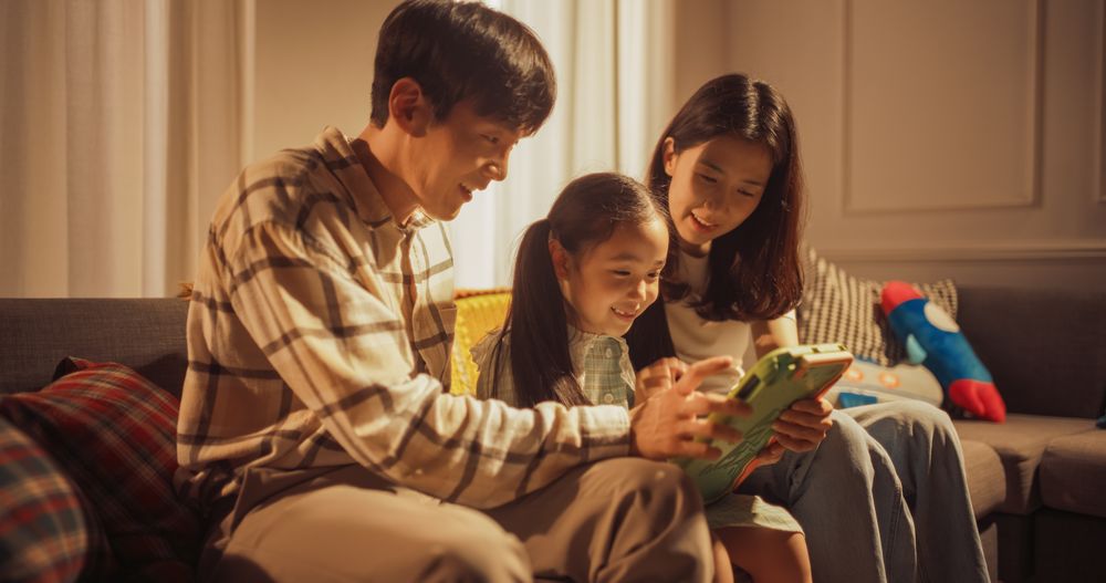 Close Up of a Korean Family Spending Time Together, Using Digital Tablet Computer at Home.