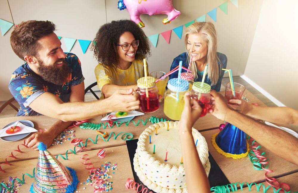 Group of people raising their drinks to toast over a cake