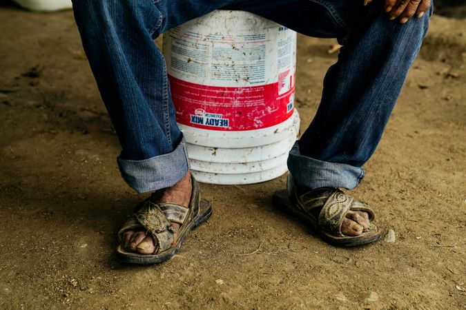 adult man resting on bucket