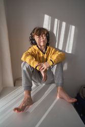 Boy in headphones sitting against wall