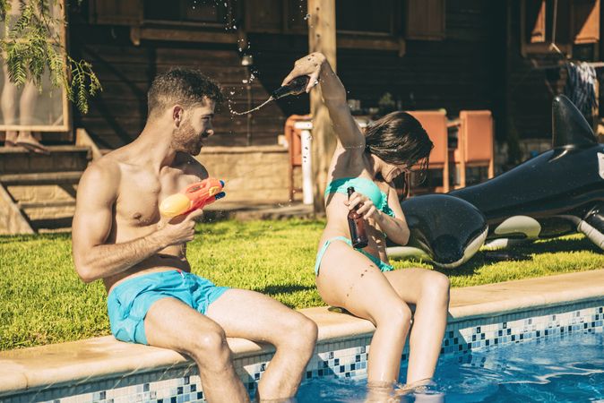 Couple having fun sitting at swimming pool