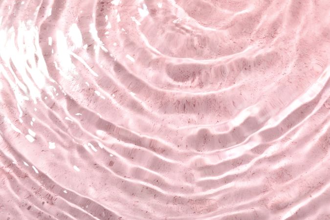 Top view of clear water in pink background with copy space