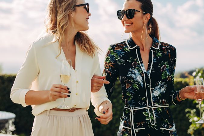 Fashionable female friends with wine outdoors