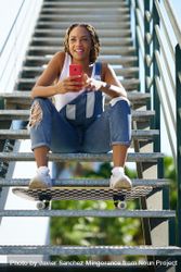 Happy female checking phone on stairs with skateboard 5qj3q4