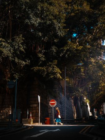A lady walks on a well-lit city sidewalk at night