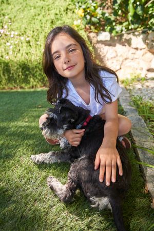 Smiling girl hugging purebred dog in nature