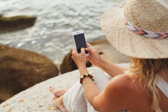 Contemporary woman with phone chilling on seashore