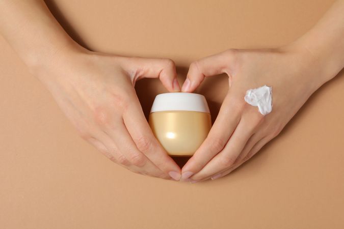 A jar of hand cream on a light, beige background.