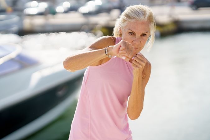 Older woman practicing boxing on a coastal pier