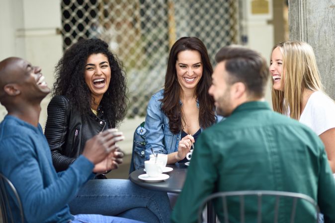 Male and female friends sitting in outdoor cafe together with coffee