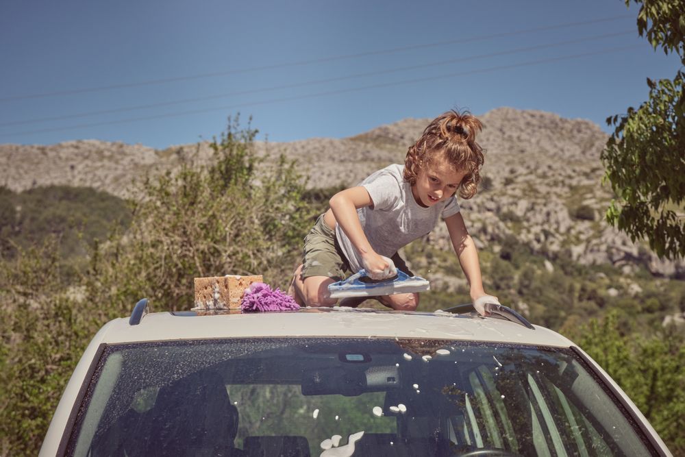 Boy washing car with window cleaning tool