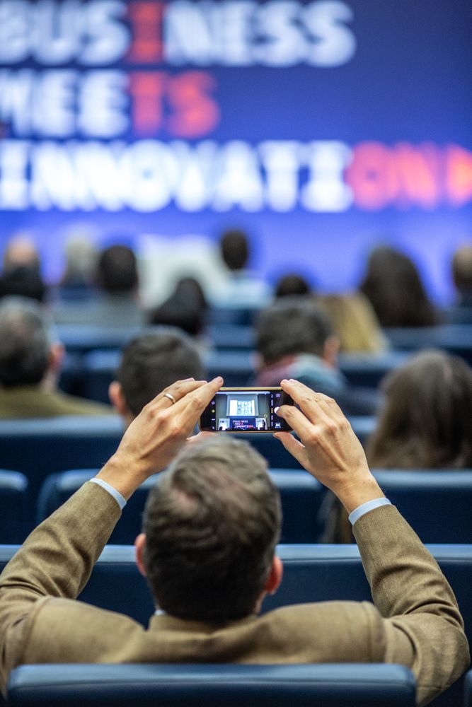 Back view of businessman taking a photo from his cellphone at business conference