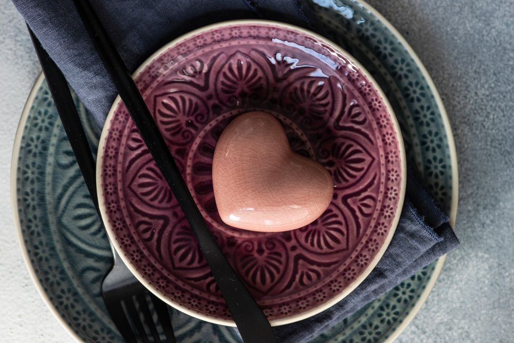 Ornate plates with pastel ceramic heart on grey counter