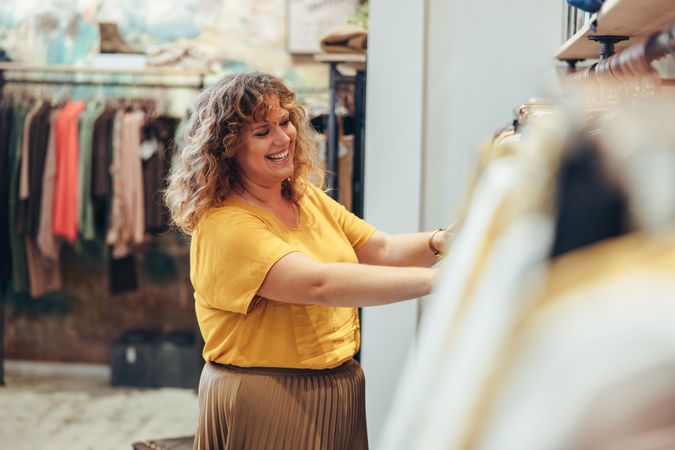 Saleswoman arranging clothes in rack of her fashion store