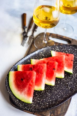 Watermelon slices arranged on plate with glass of wine