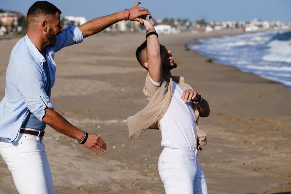 Happy gay couple dancing on seaside