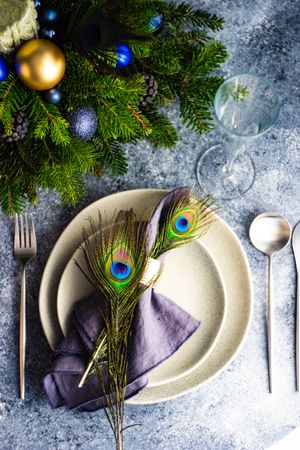 Top view of festive table setting for Christmas dinner with peacock feathers