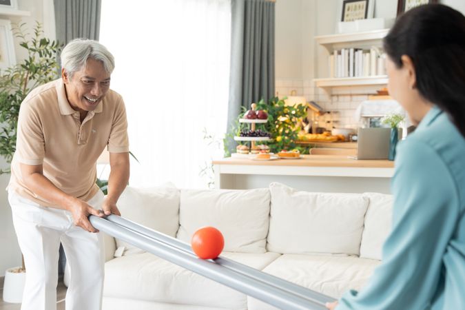 Asian couple playing rolling ball for practice balance and concentrate in the living room