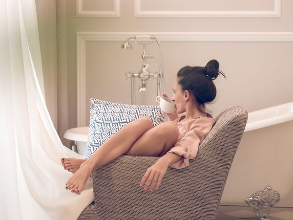 Relaxed woman drinking coffee in comfortable armchair