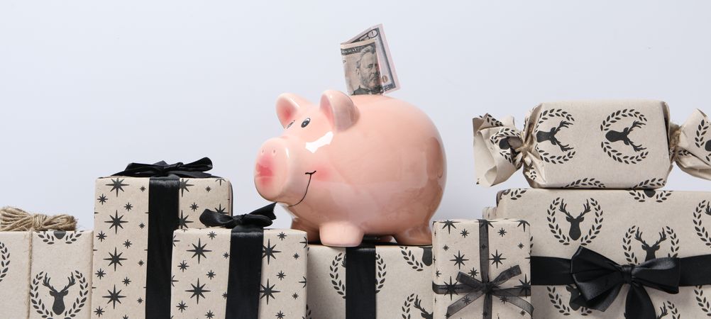 Piggy bank with cash on gift boxes on neutral background, close up