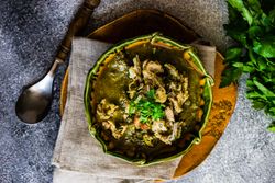 Top view of Georgian chakapuli stew on counter with fresh herbs