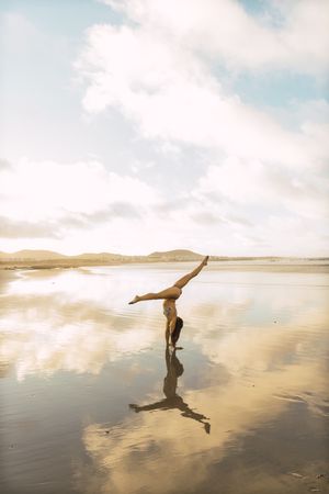 Woman doing handstand near sea