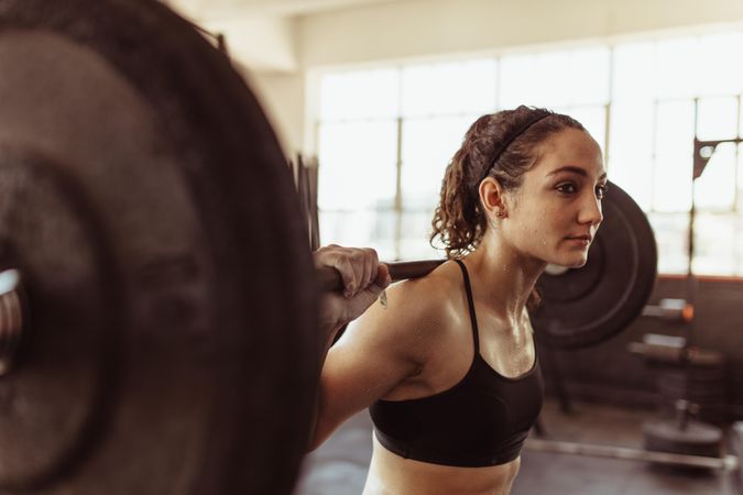Healthy young woman at gym exercising with barbell